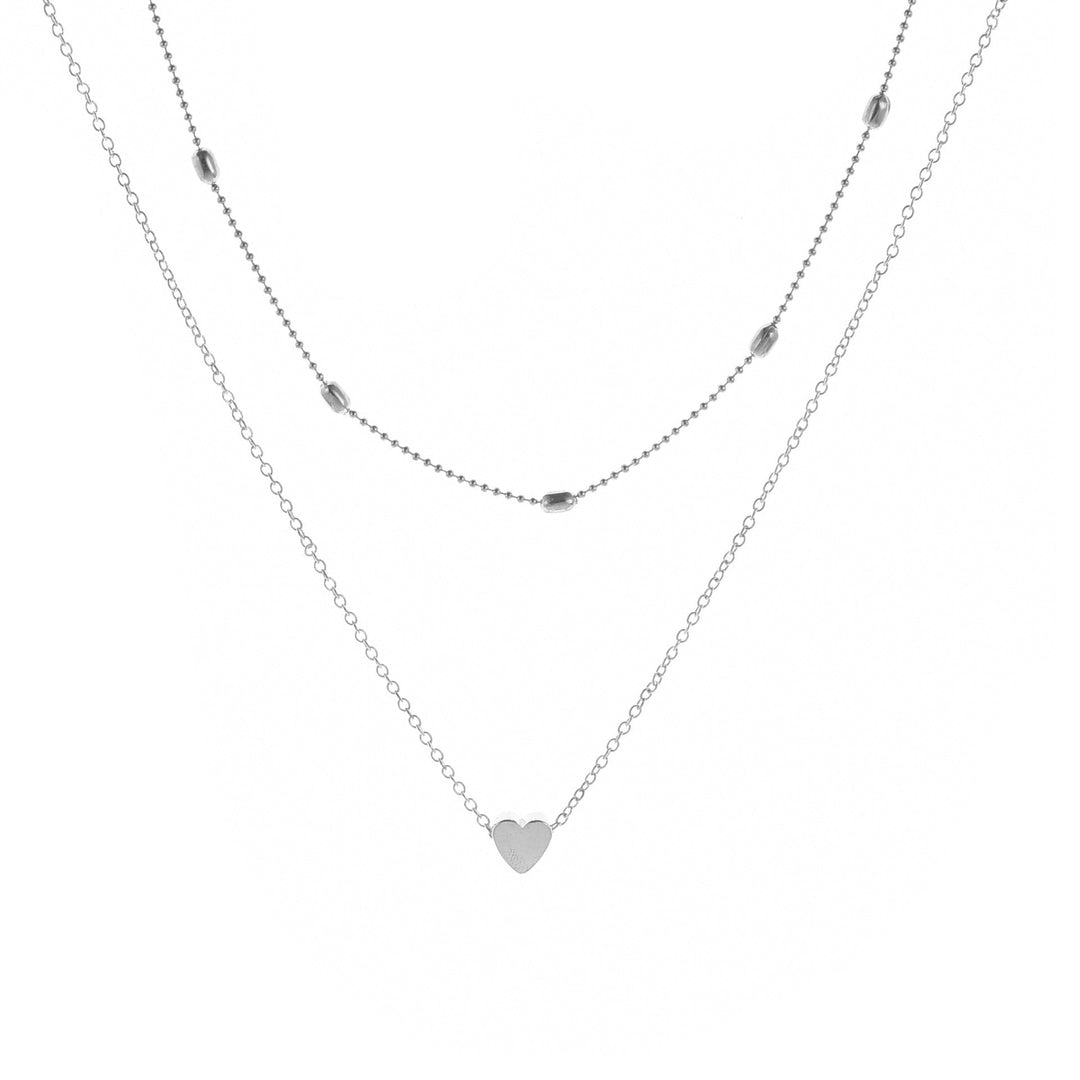 Woman wearing an elegant gold layered necklace with a heart charm, delicate and stylish accessory.