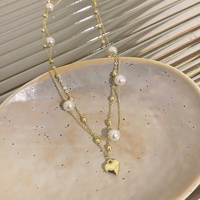 Beautiful women's layered heart charm necklace in pearl color. A trendy and elegant jewelry gift for her.