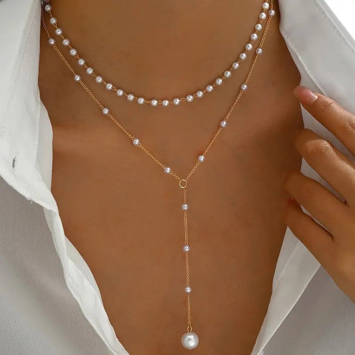 Close-up of a white layered pearl necklace with shimmering gold chains, stylish women's jewelry.