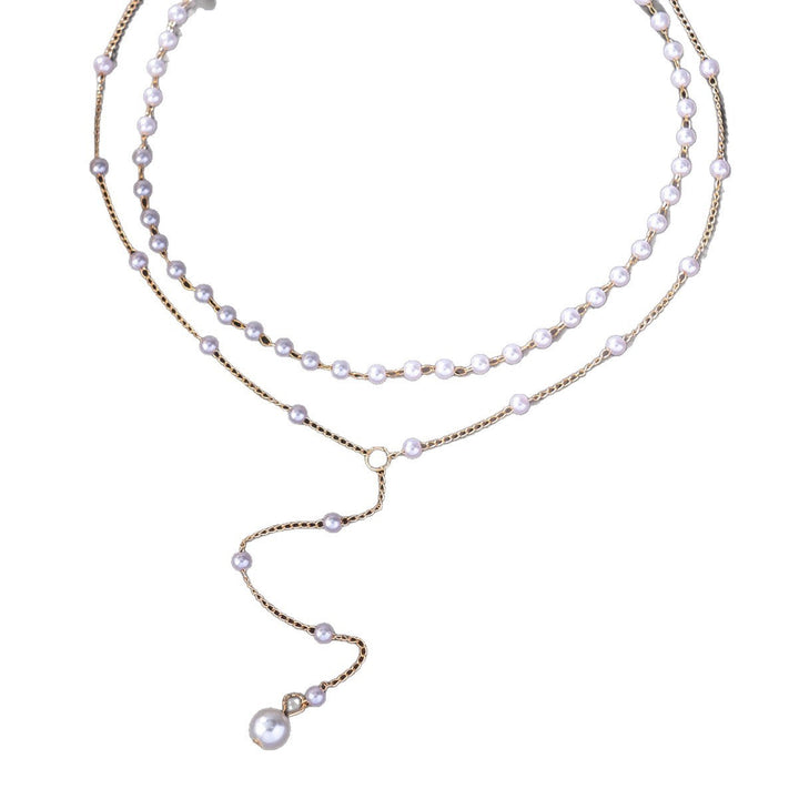 Detailed view of a women's layered pearl necklace featuring lustrous white pearls & gold chains.