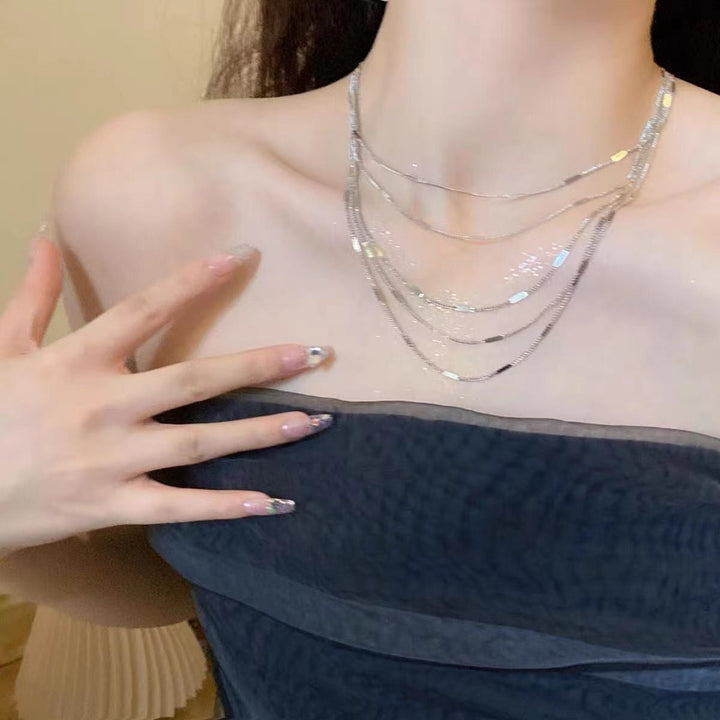Woman wearing an elegant layered silver chain necklace, a fashionable and delicate jewelry piece for daily wear.