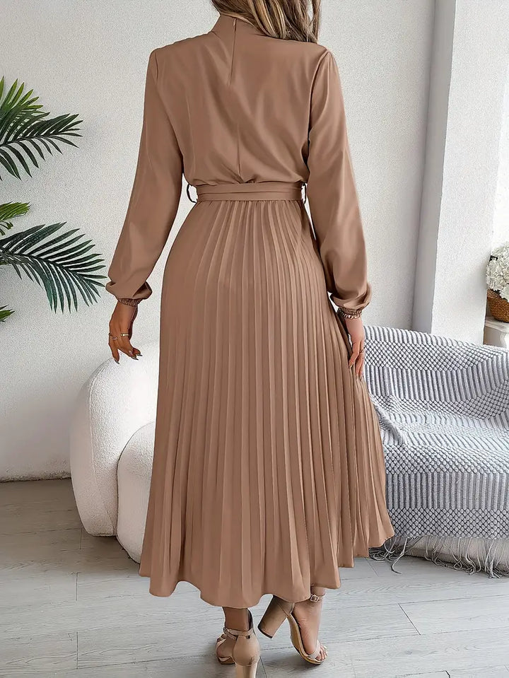 Close-up of elegant women's long-sleeve belted midi dress, showcasing pleated details & flattering fit.