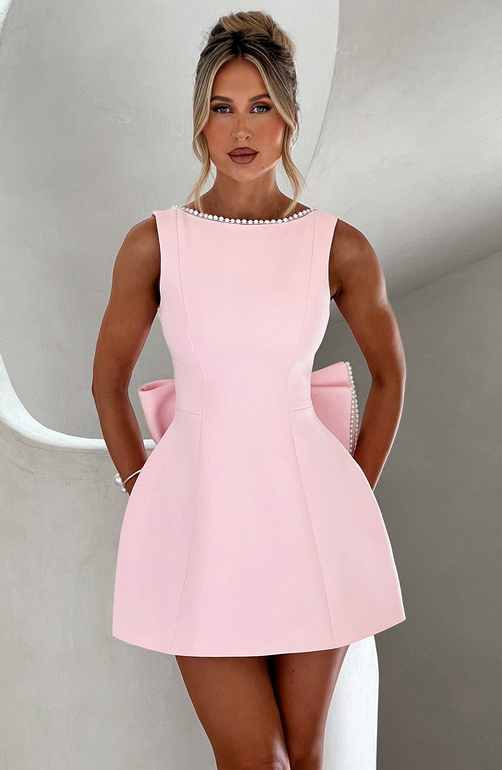 Elegant women's mini dress with pearl trim and a statement bow back.