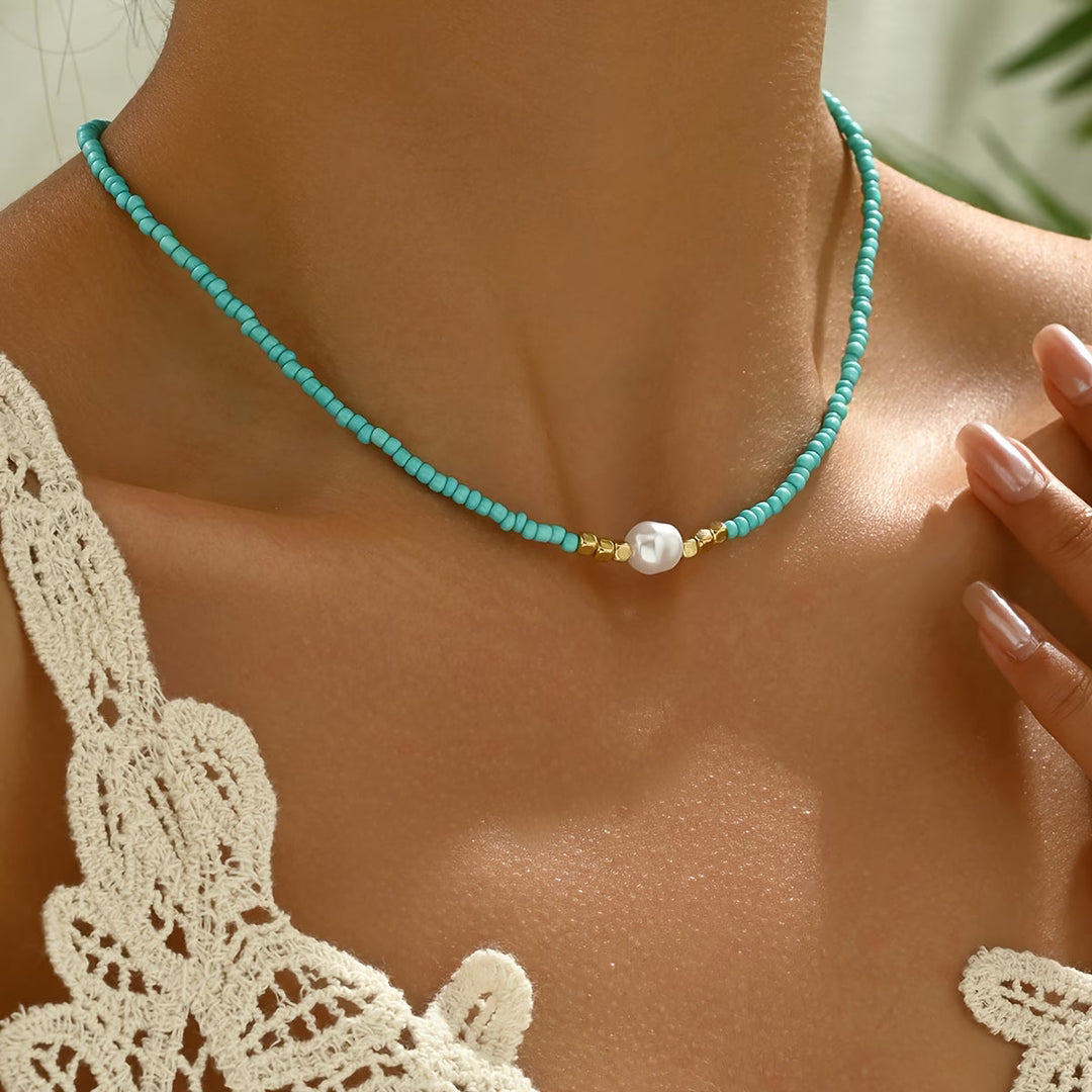 Minimalist women's necklace featuring a delicate white pearl and a vibrant turquoise stone on a fine chain.