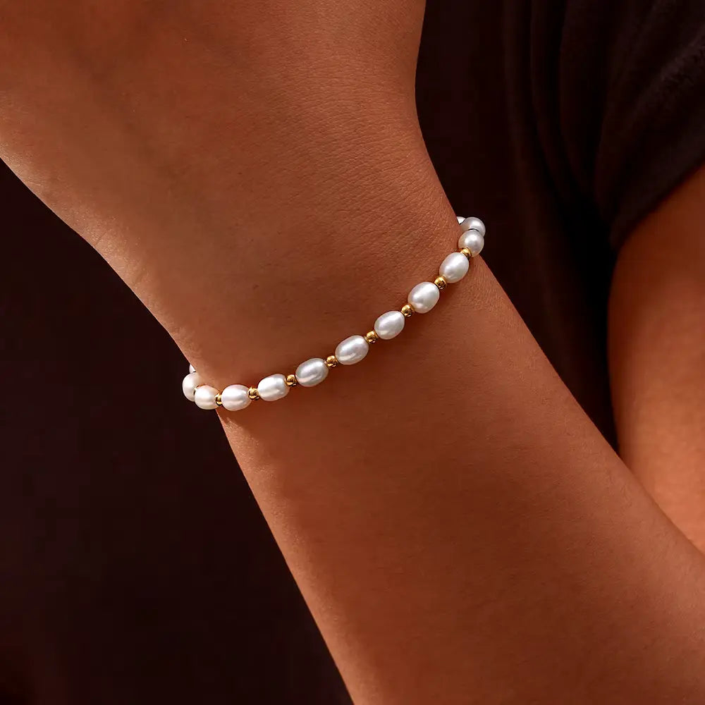 Close-up of a women's elegant pearl and gold bracelet, showcasing delicate design & lustrous pearls.