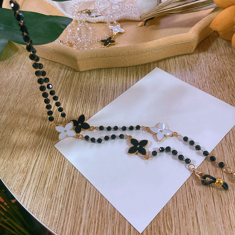 Close-up of a sophisticated pearl necklace featuring delicate gold-tone floral charms and adjustable chain.