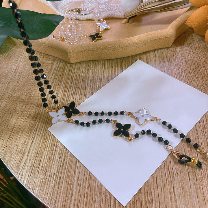 Close-up of a sophisticated pearl necklace featuring delicate gold-tone floral charms and adjustable chain.