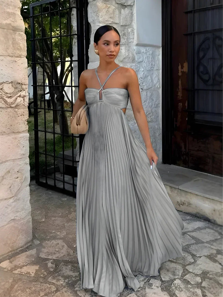 Halter neck pleated maxi dress for women, featuring a long flowy skirt & chic side cut-outs. Elegant party attire.