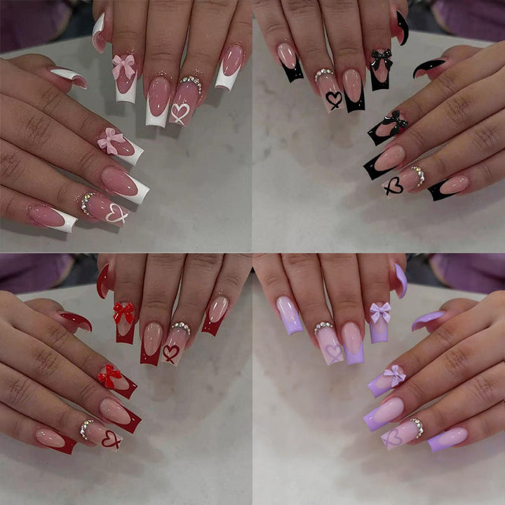 Elegant women's press-on nails with artistic black tips, charming bows, and heart designs.