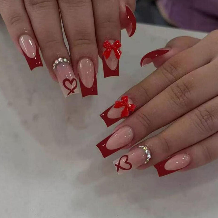 Artistic press-on manicure set for women, showcasing trendy black tips, bows, and heart accents.