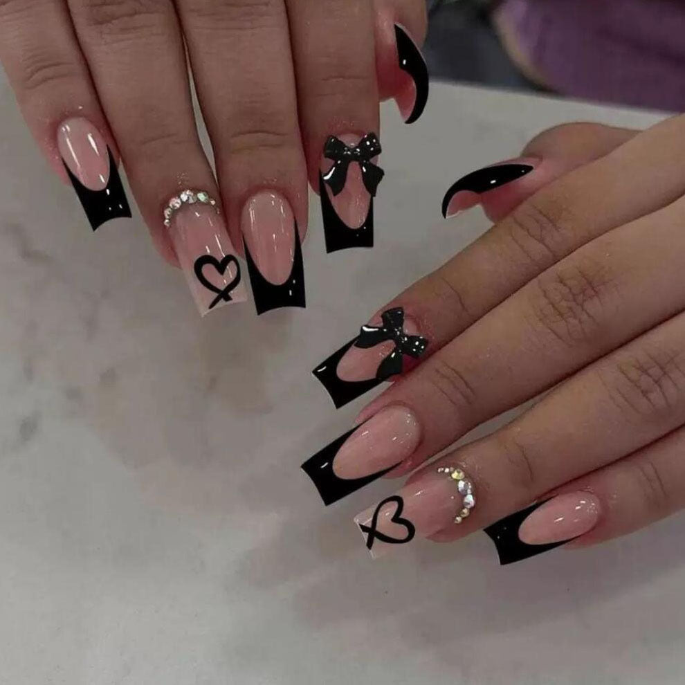 Stylish press-on nails for women, featuring a unique black tip design, bows, and heart nail art.