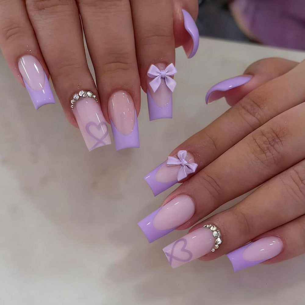 Fashionable false nails with a sleek black tip, pretty bows, and charming heart nail art for women.
