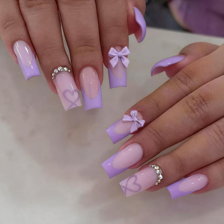 Fashionable false nails with a sleek black tip, pretty bows, and charming heart nail art for women.