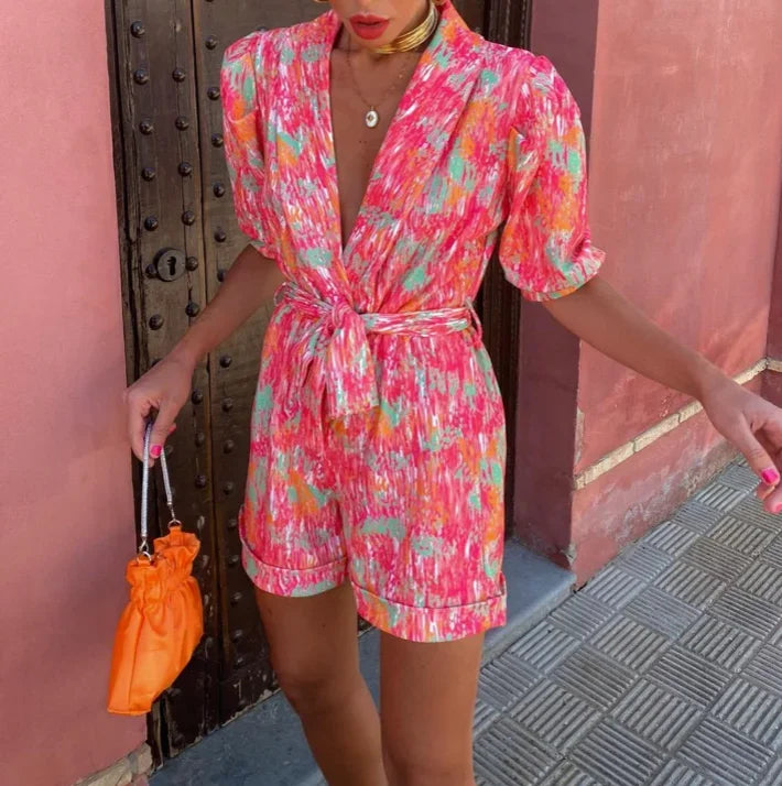 Fashionable wedding guest romper in lilac, featuring elegant puff sleeves and a complementing belt.