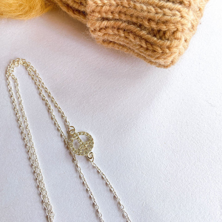 Graceful filigree peace sign pendant necklace, an elegant silver women's accessory for a subtle statement.