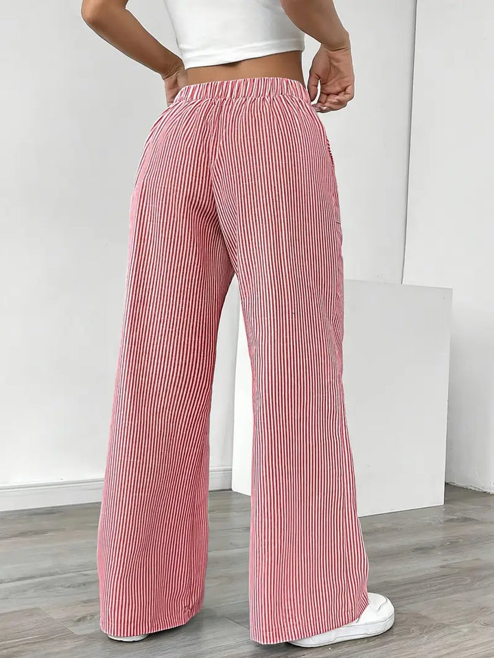 Women's elegant striped wide-leg pants flowing gently, featuring stylish pockets.
