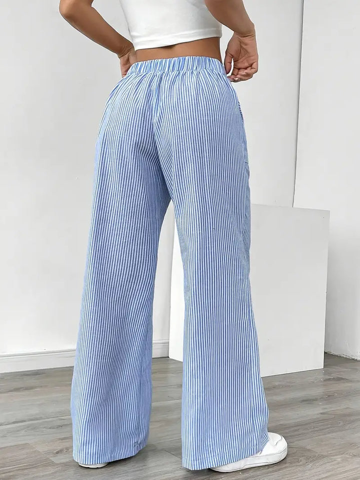 Women's striped wide-leg pants with pockets, shown in a walking pose to emphasize flow.