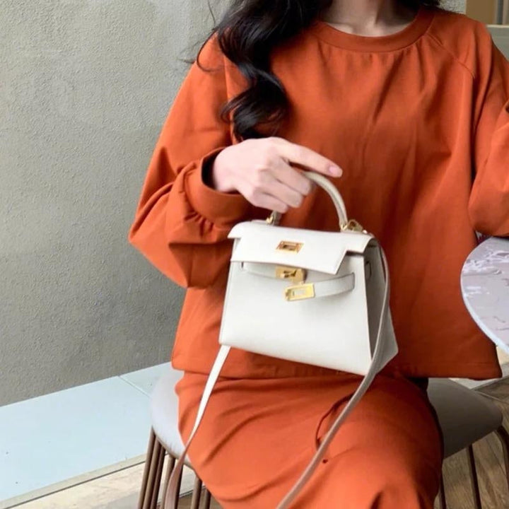 Luxury women's top handle handbag, classic design with a modern gold lock, ideal for elegant fashion.