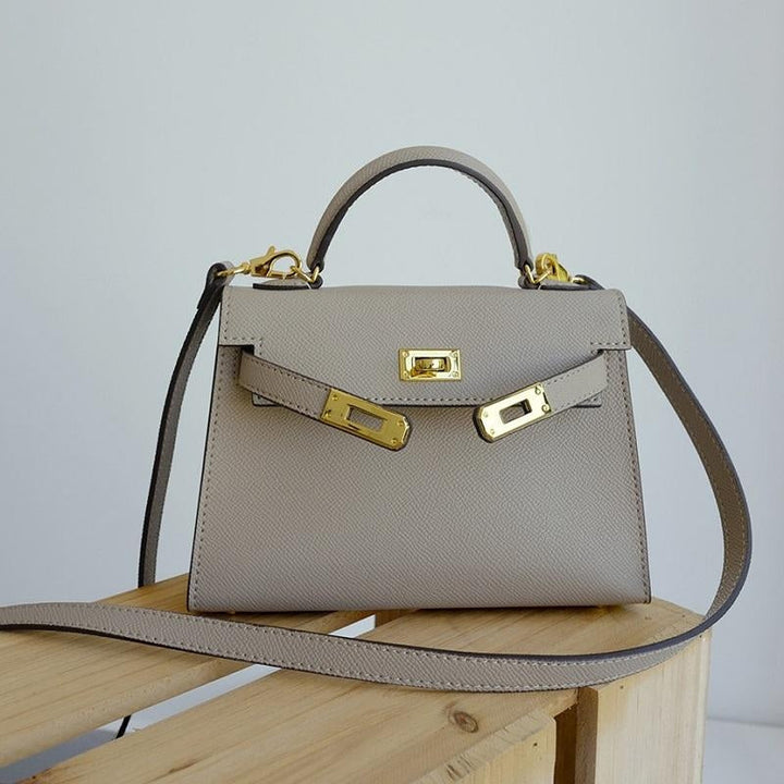 Structured women's top handle purse, featuring a bold gold lock, perfect for a polished look.