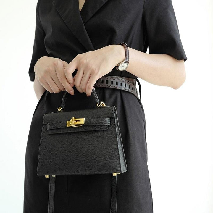 Fashionable ladies' accessory: a top handle bag with a sophisticated silhouette and gold lock clasp.