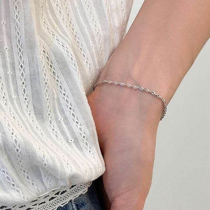 Close-up of an elegant women's gold twisted chain bracelet, showcasing its unique texture and shine.