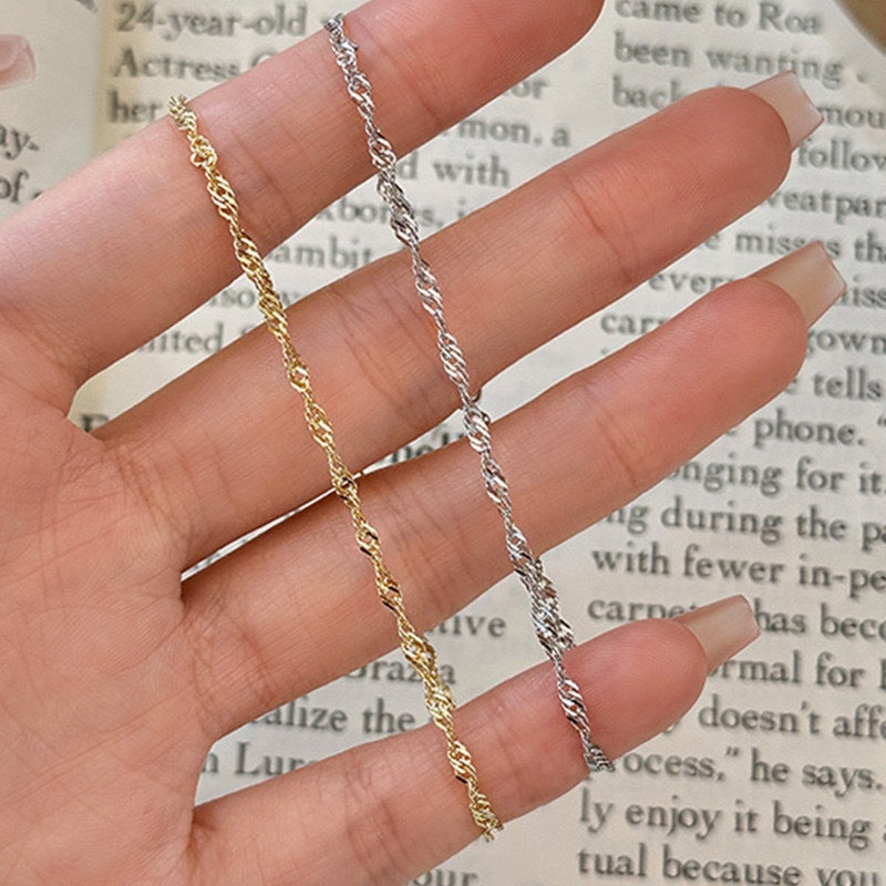 Women's wrist wearing an elegant gold twisted chain bracelet, a chic and adjustable fashion accessory.