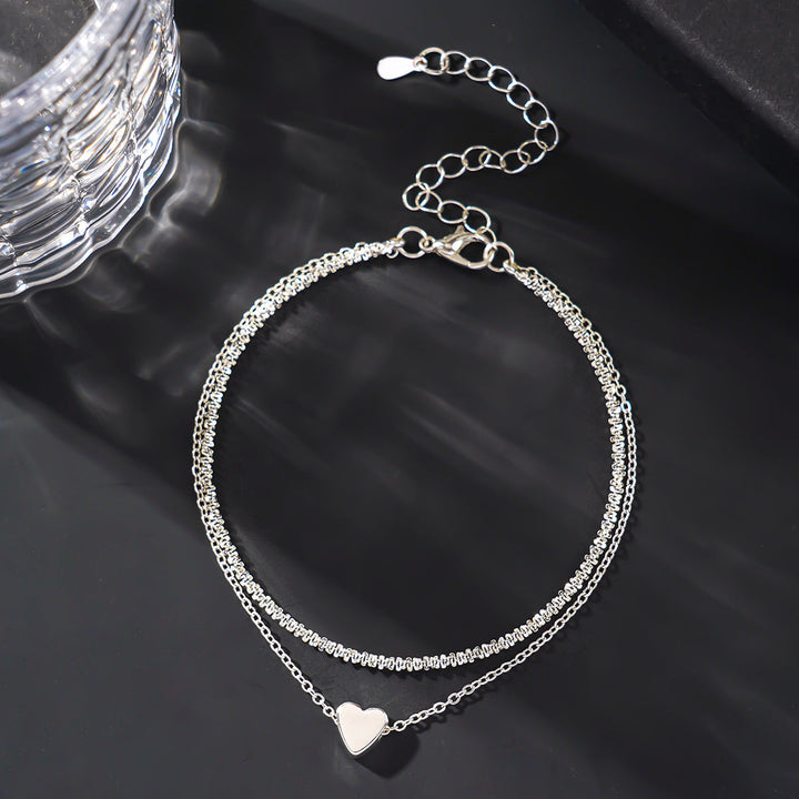 Fashionable women's two-tone heart charm anklet, a dainty silver & gold ankle bracelet for elegant summer style.