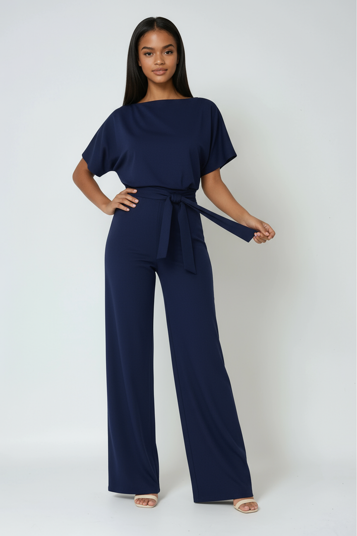 Back view of a flowing women's wide-leg jumpsuit with a chic tie waist, showcasing its elegant and comfortable design.