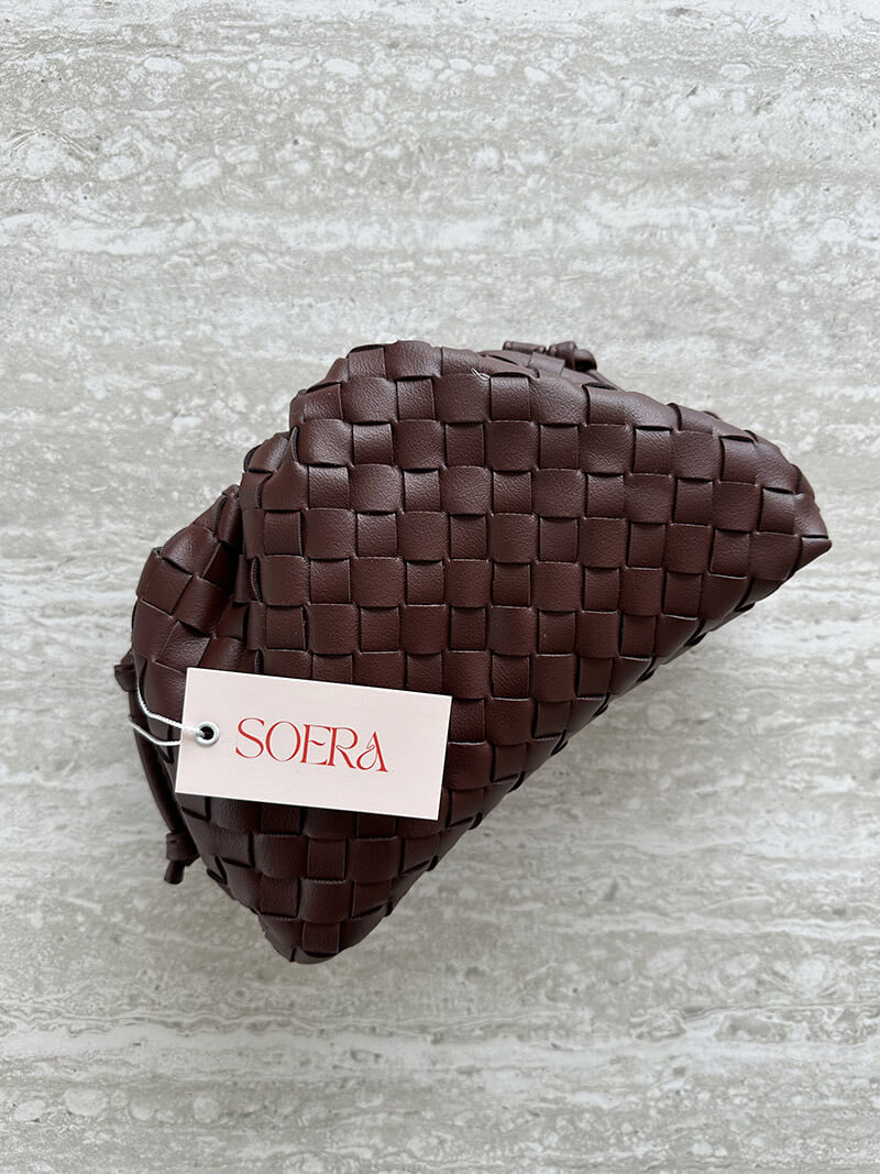 Detail of the comfortable strap on an elegant women's woven shoulder bag. Modern, compact everyday design.