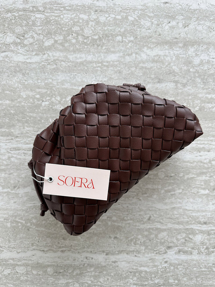 Detail of the comfortable strap on an elegant women's woven shoulder bag. Modern, compact everyday design.
