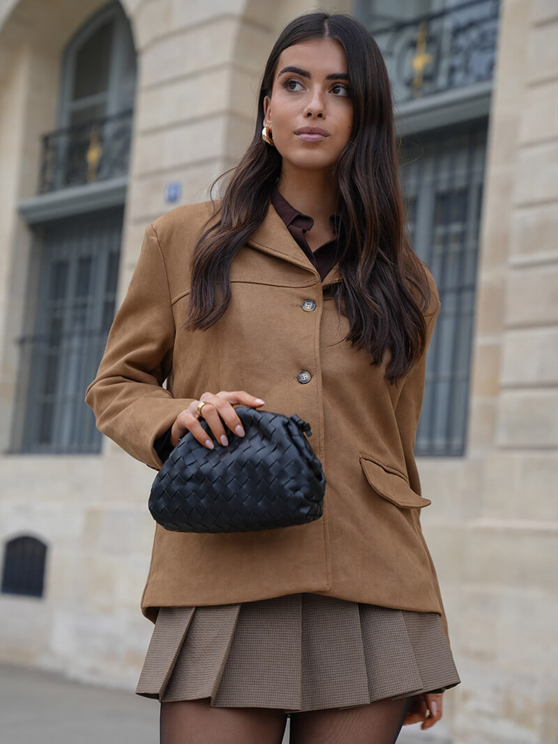 Stylish woman carrying a modern woven shoulder bag, ideal for everyday elegance. Versatile & compact handbag.