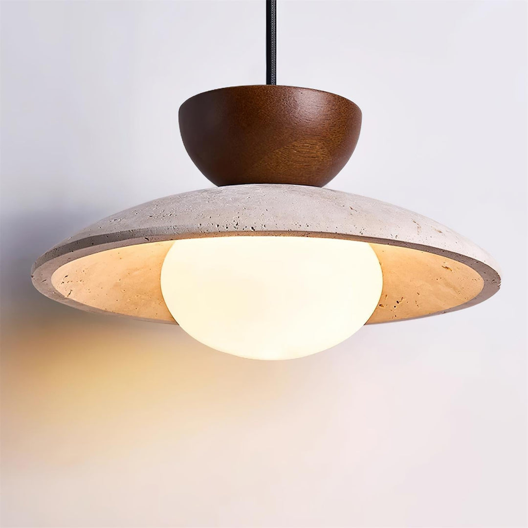 Yarelle pendant light installed over a dining table. Modern fixture with travertine, wood, & glass elements.
