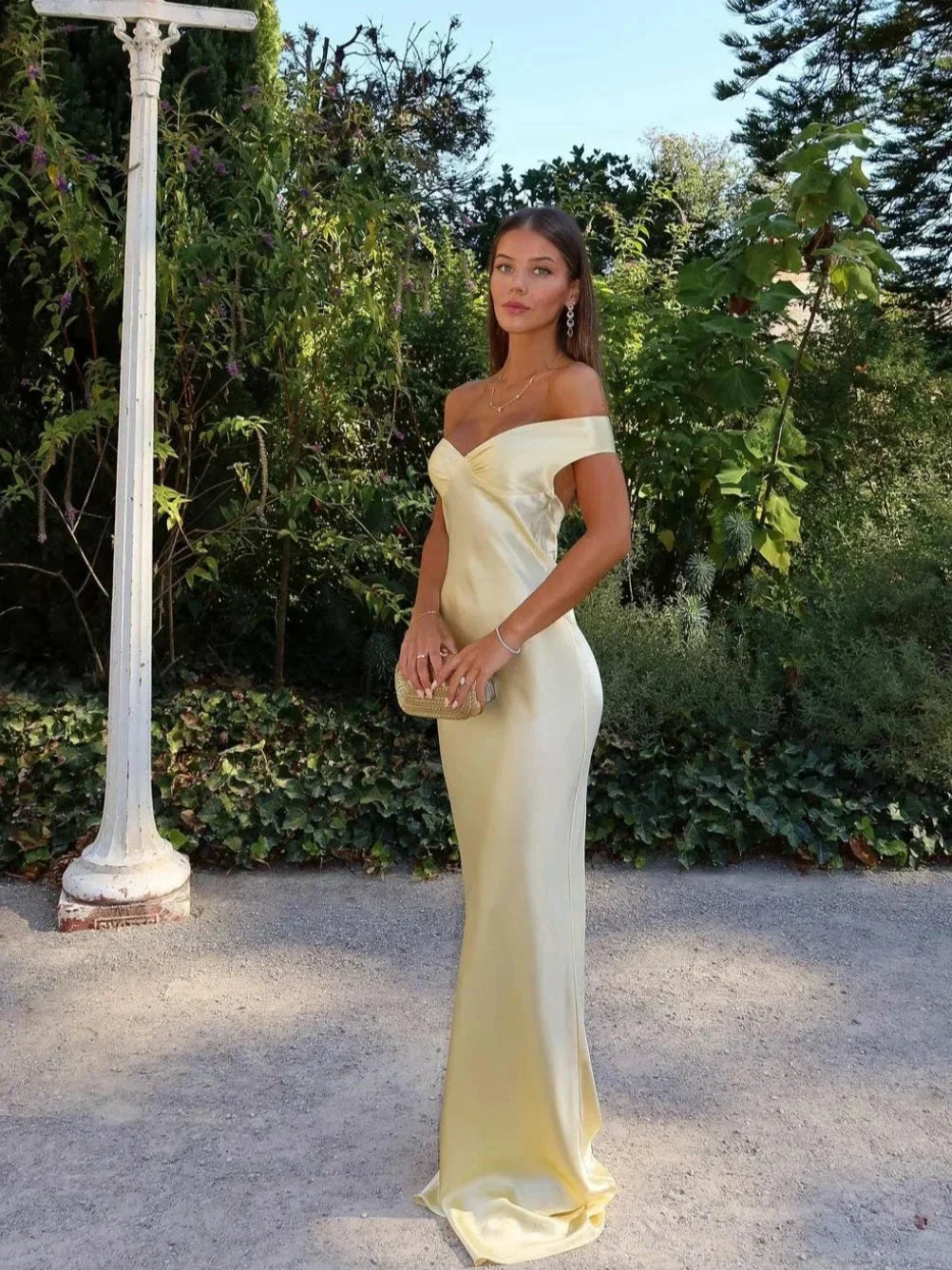 Elegant yellow off-shoulder maxi evening dress for women with a matching clutch bag for formal occasions.