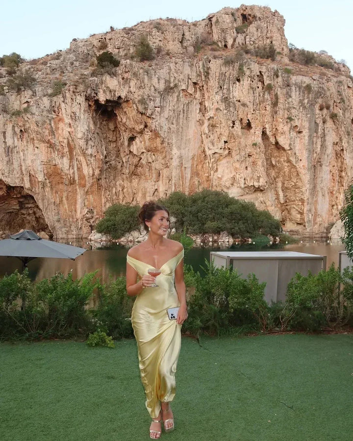 Sophisticated yellow off-shoulder maxi dress for women's elegant formal events, complete with a trendy clutch.