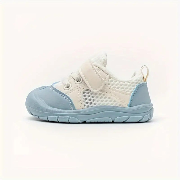 Infant in flexible, non-slip barefoot shoes, ideal for crawling and promoting natural foot development.