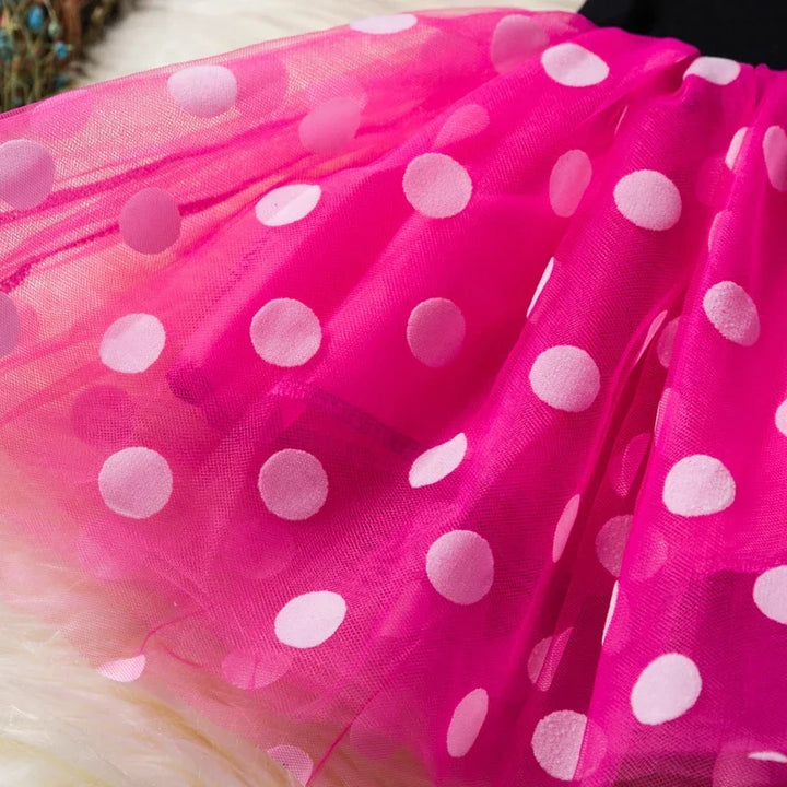 Little girl enjoying playtime in her Minnie Mouse costume, featuring a polkadot dress, ears, and bow.