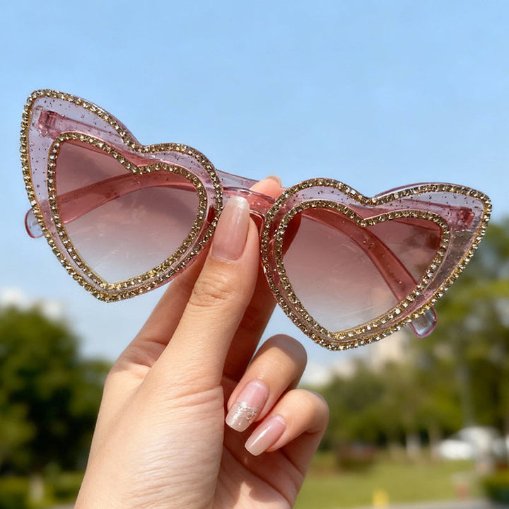 Close-up of women's glamorous heart-frame sunglasses, highlighting rhinestone embellishments.