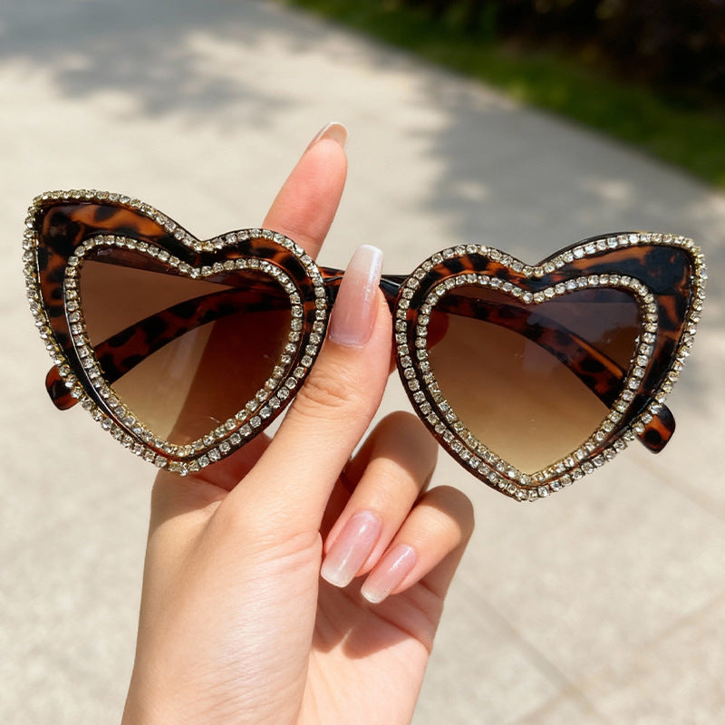 Women's elegant heart frame sunglasses. Rhinestone embellished, offering UV protection as a chic accessory.