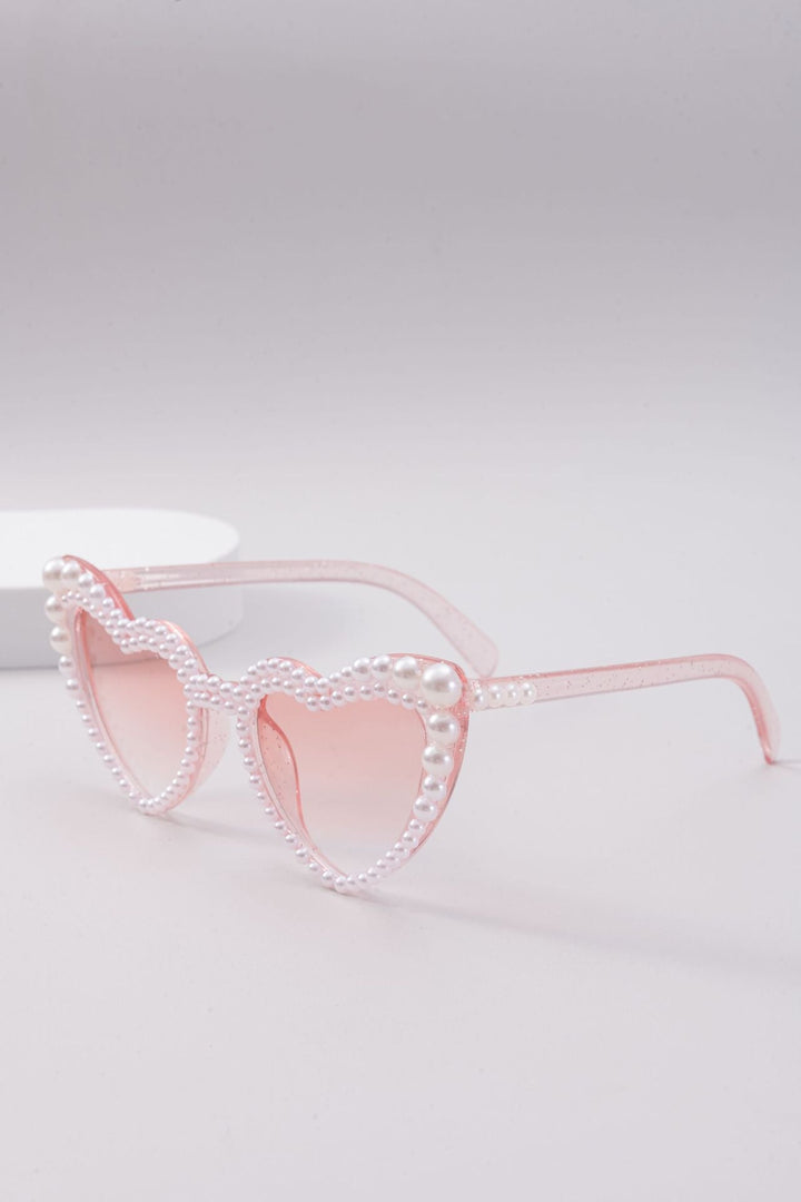 Side view of trendy heart-shaped sunglasses, women's glamorous eyewear with subtle pearl details.