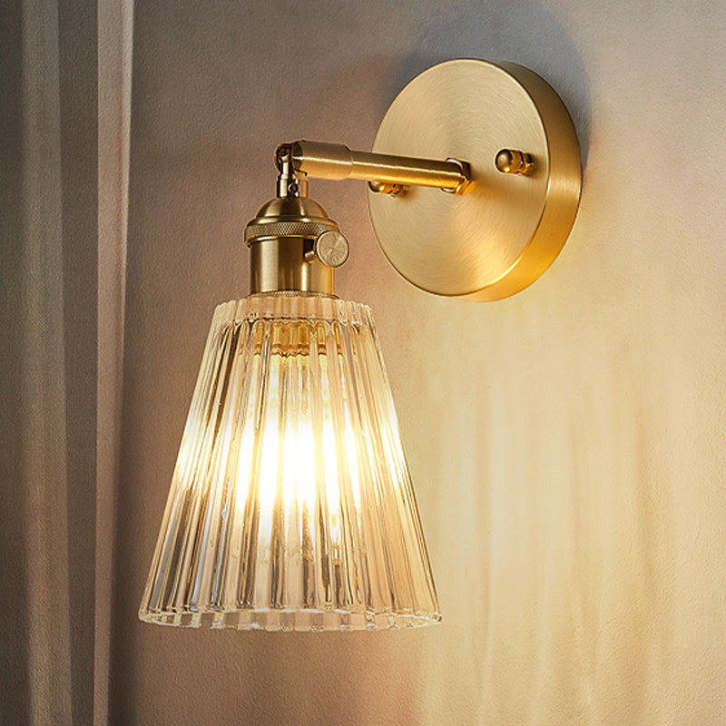 Elegant industrial brass wall sconce with tapered clear glass fixture, modern home lighting for accent decor.