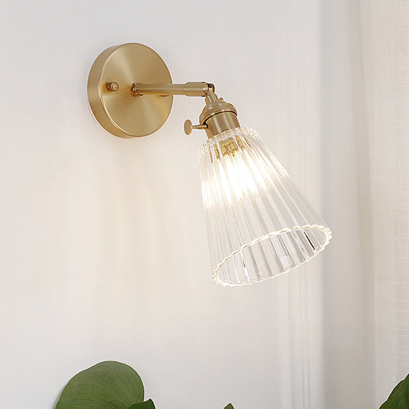 Modern industrial brass wall sconce, tapered clear glass, single light fixture, sophisticated accent home lighting.