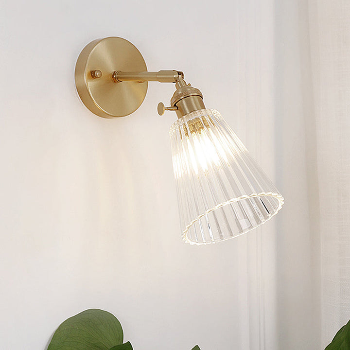 Modern industrial brass wall sconce, tapered clear glass, single light fixture, sophisticated accent home lighting.