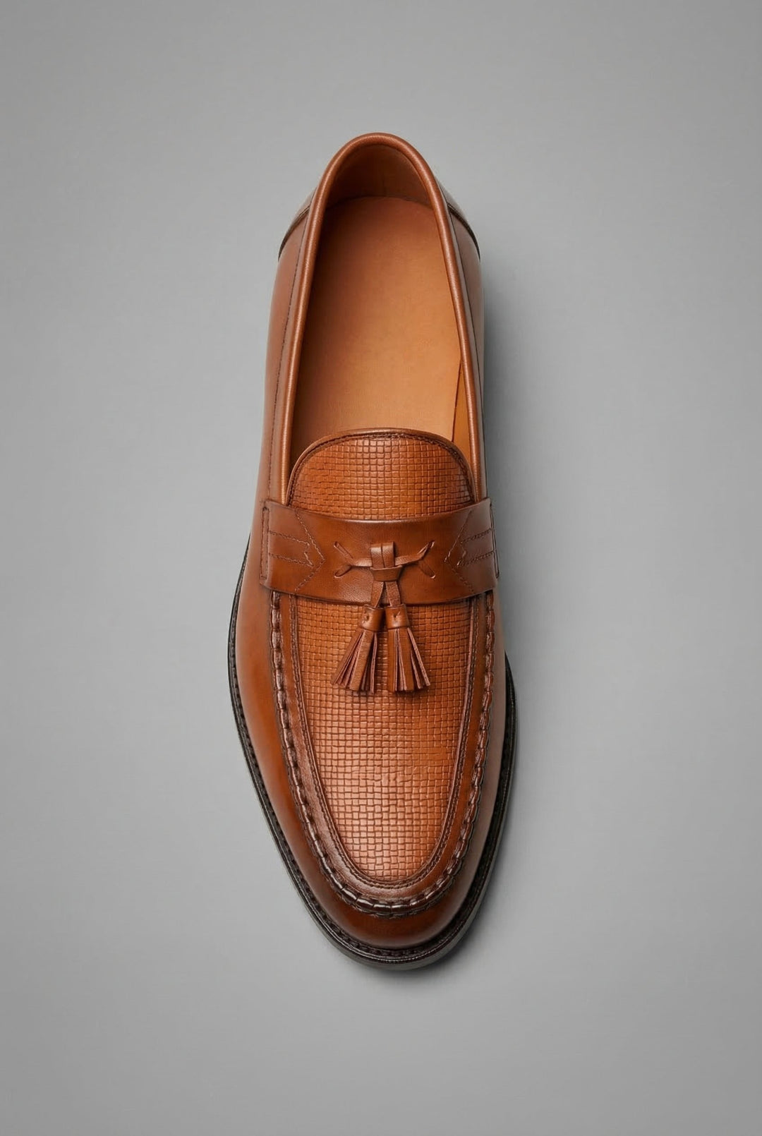 Modern men's formal loafers with a unique woven texture and decorative tassels.