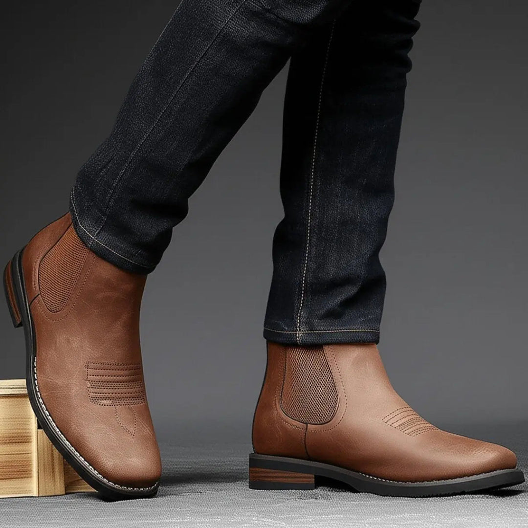 Close-up of men's black leather Chelsea boots, showcasing western stitch, elastic gusset & block heel.