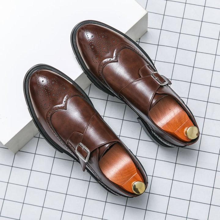 Detailed view of a men's tan leather monk strap brogue dress shoe, showcasing wingtip and perforation patterns.