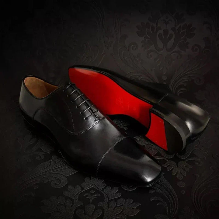 Side profile of elegant men's black Oxford dress shoes, highlighting the signature red sole and sleek design.
