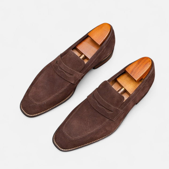 Polished dark brown men's penny loafers. Smooth leather slip-on dress shoes for a refined, classic look.