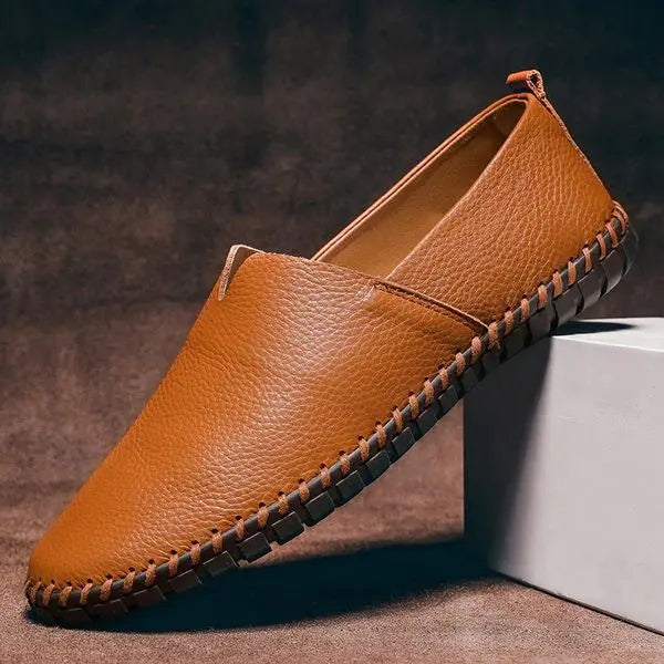 Close-up of comfortable men's hand-stitched brown leather loafers, showing intricate stitching and slip-on design.
