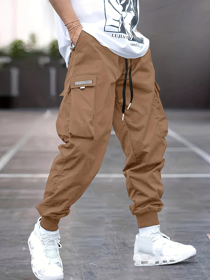Stylish men's jogger cargo pants with a drawstring, multiple pockets, and ankle cuffs for a modern casual look.
