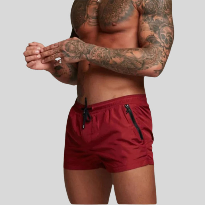 Men's drawstring swim shorts with zip pockets, ideal for beachwear & summer fashion. Quick-dry fabric.